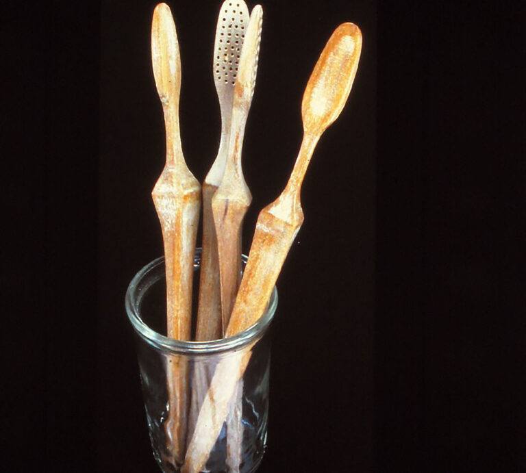 Wooden toothbrushes missing their bristles in a glass cup