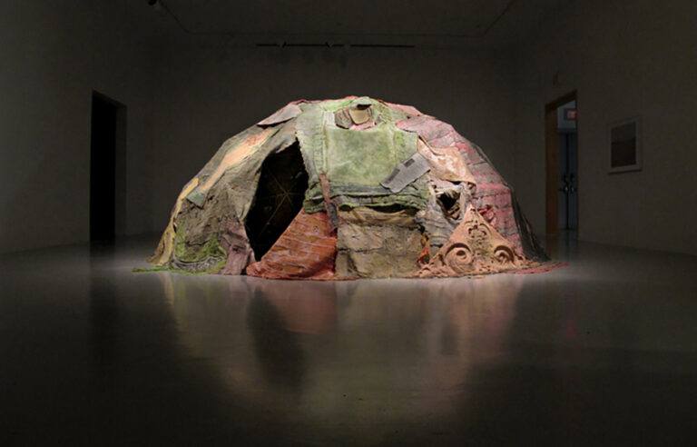 A large dome sculpture with fragments of fabric draped over it