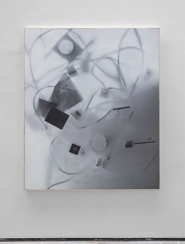 A framed abstract image of items in black and white on a white ground