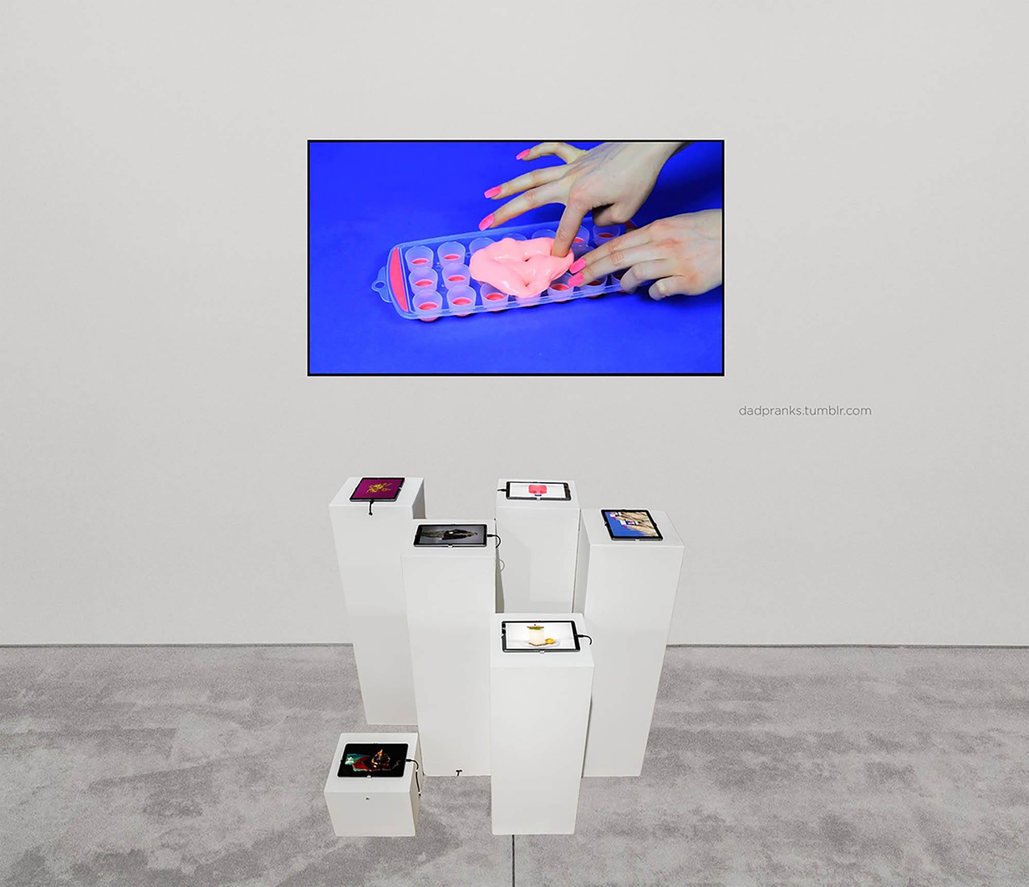 An installation image of a screen showing hands pushing putty into an ice tray, with smaller screens on pedestals