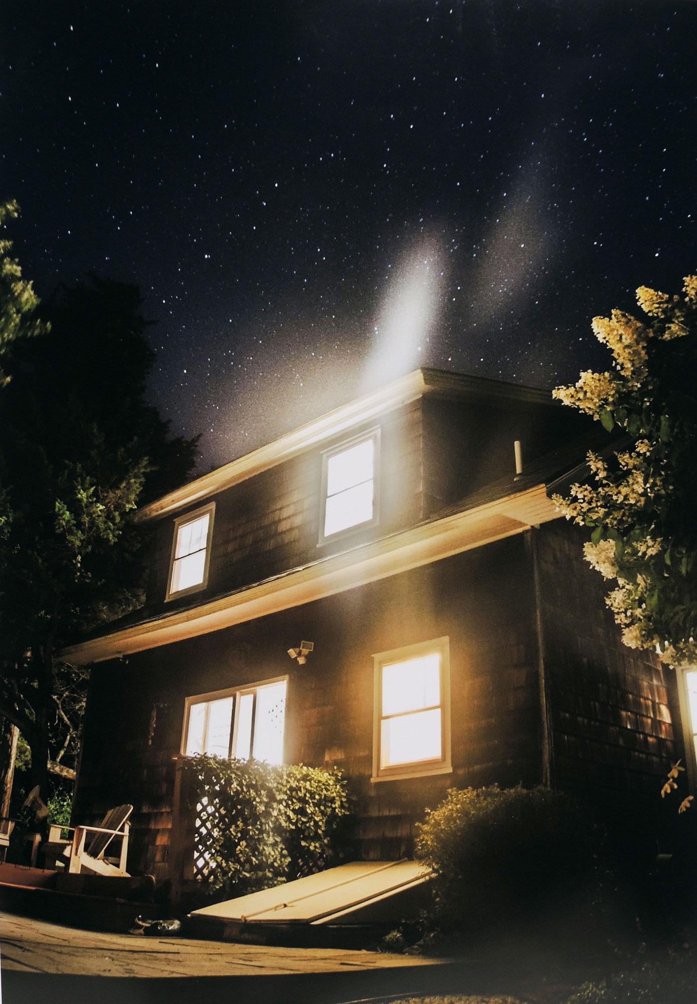 A photograph by Gabrielle Robinson of a house illuminated from the inside on a starry night