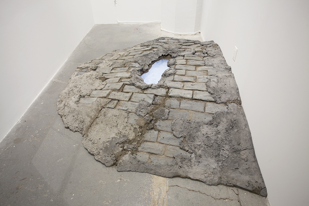An installation image showing a concrete or dirt mound with stone texture and a hole at its center