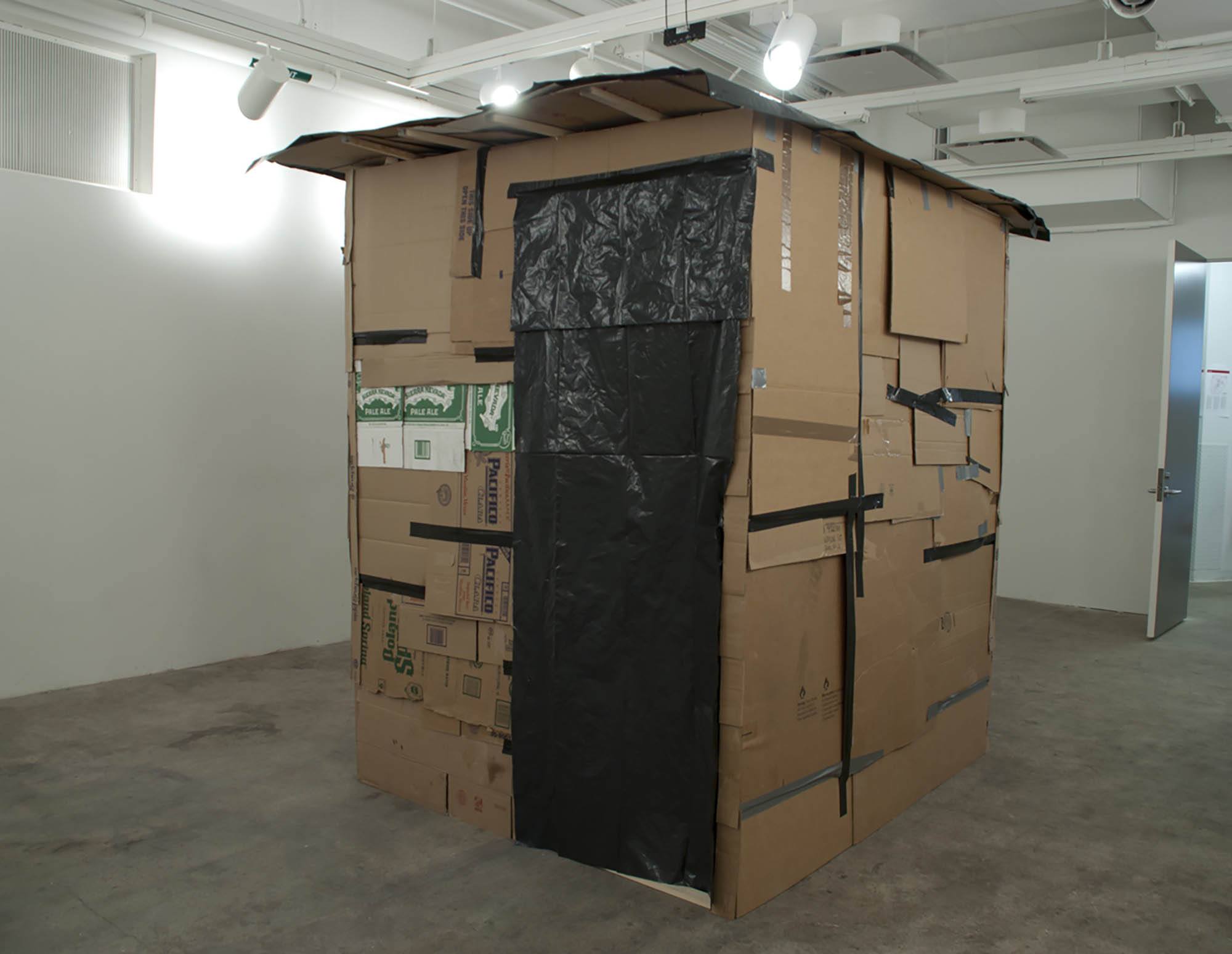 A shelter build out of cardboard inside a gallery