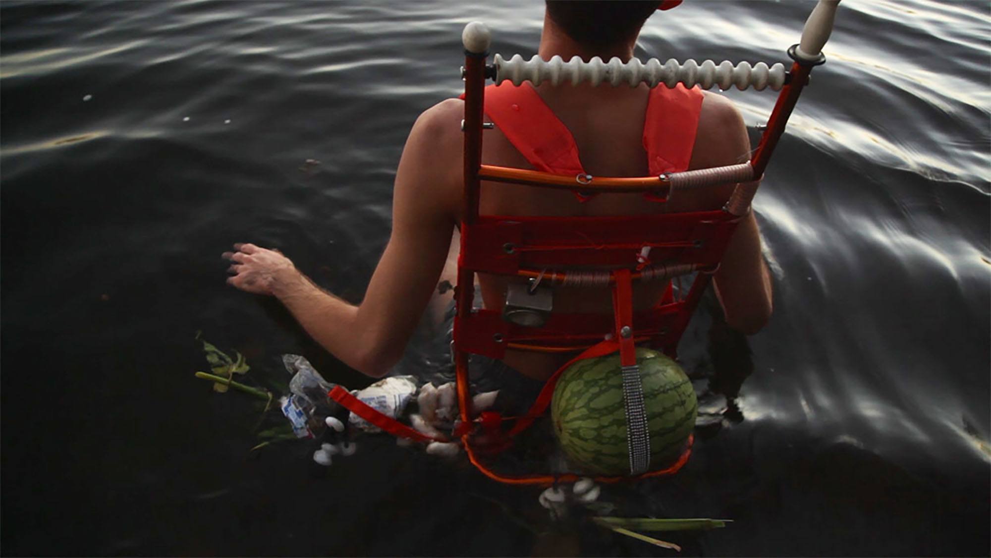 A person sitting in a chair submerged in water with objects attached by straps