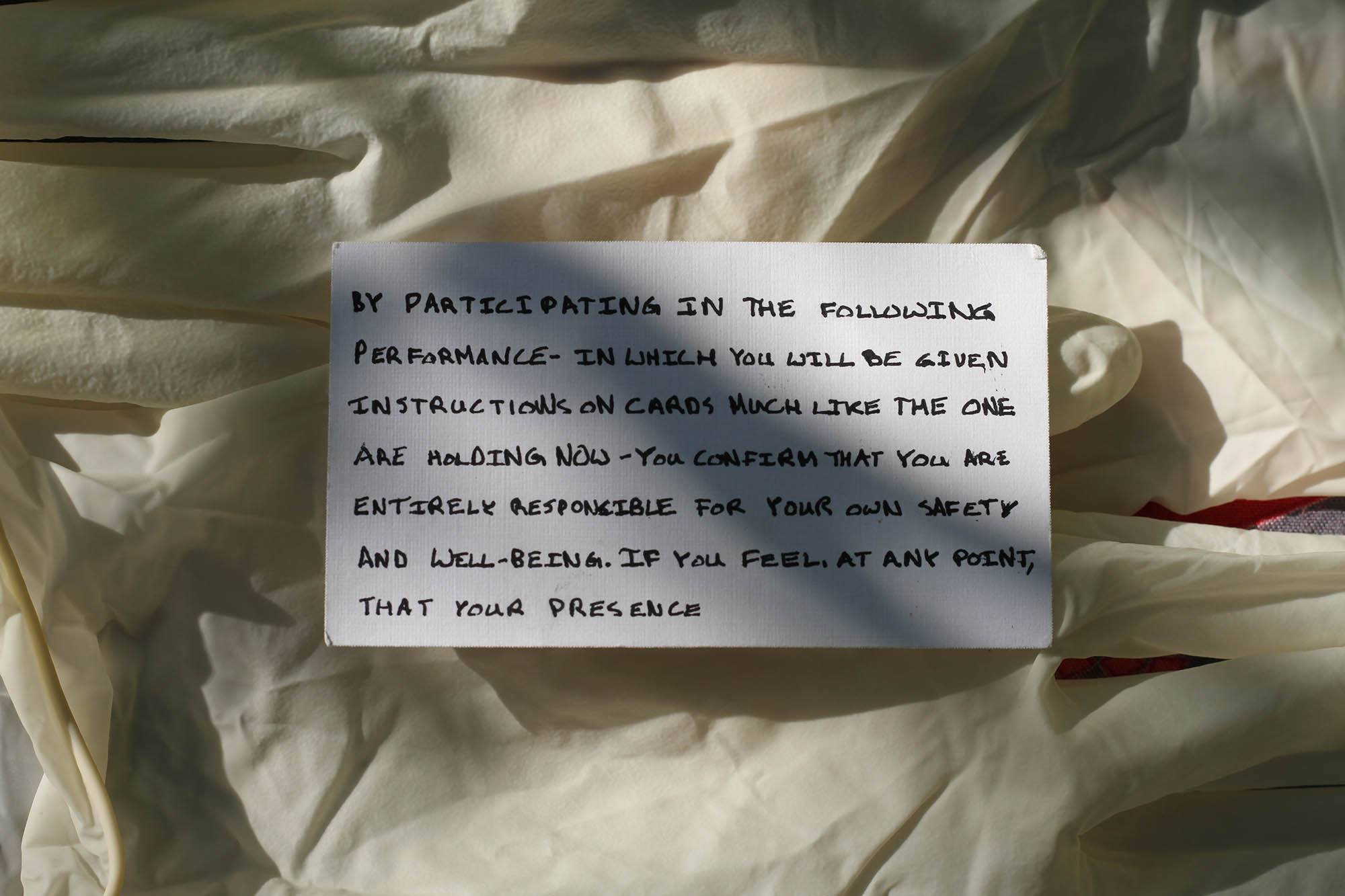 A notecard that reads "by participating in the following performance - in which you will be given instructions on cards much like the one you holding now - you confirm that you are entirely responsible for your own safety and well-bring. If you fell, at any point, that your presence"