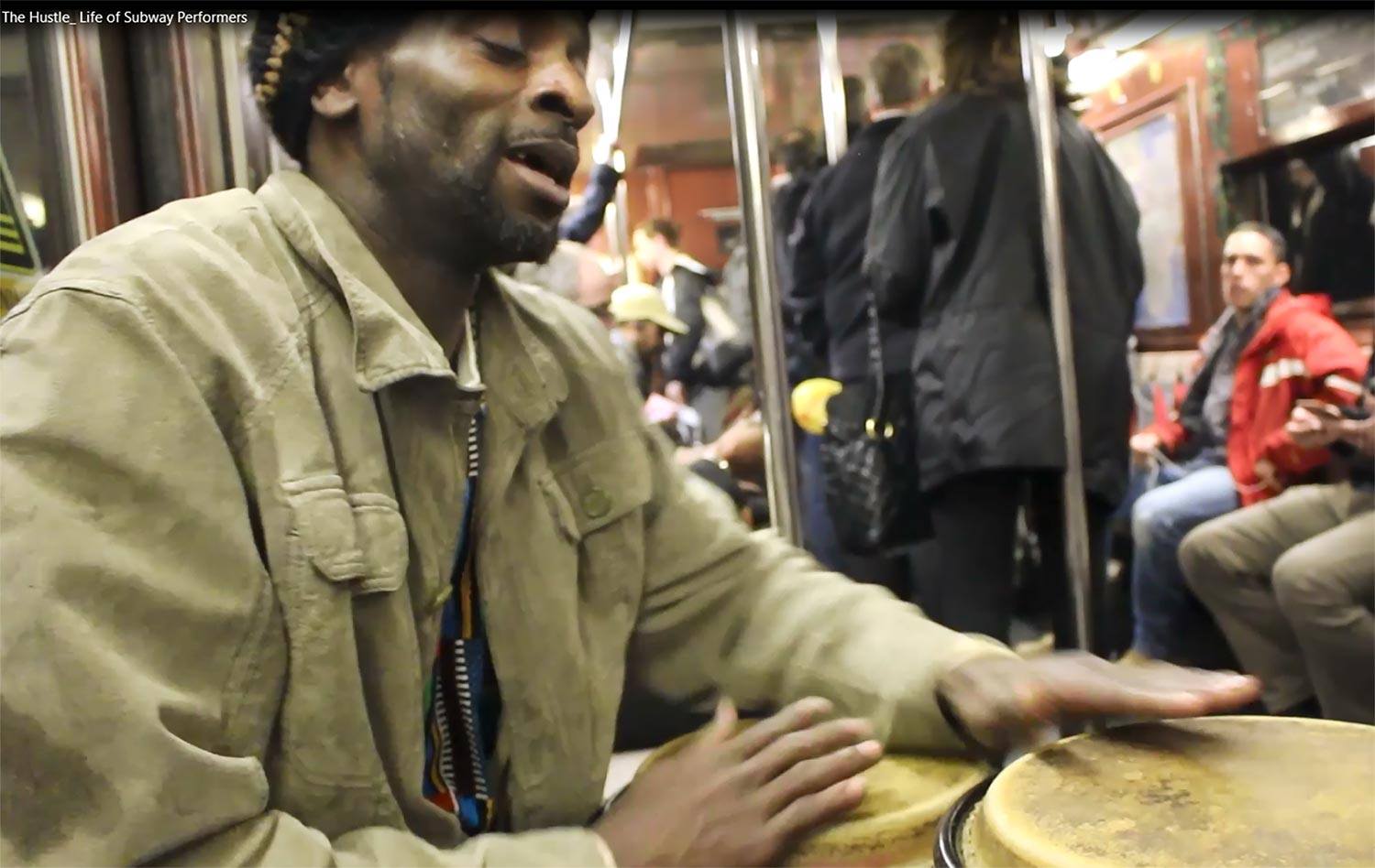 A person singing and playing the drums on the subway
