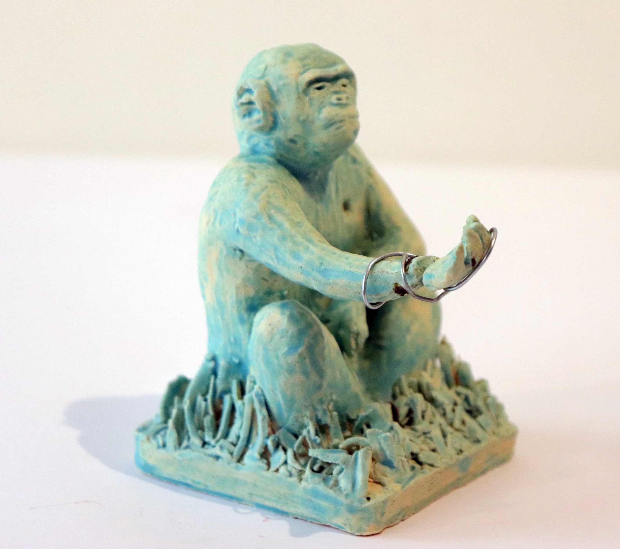 A small turquoise sculpture of a n ape