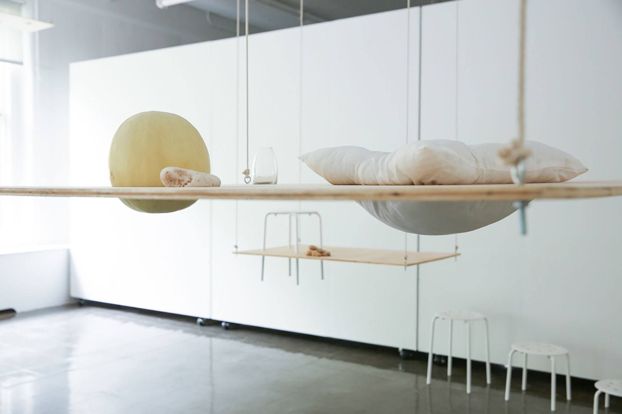Suspended sheets of plywood with hard and soft objects resting in holes cut in the wood