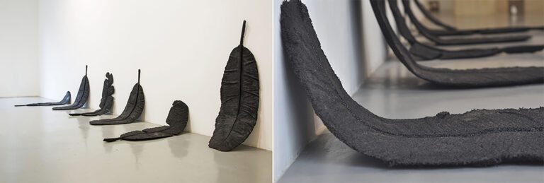 Banana leaves cast in rubber resting against a gallery wall