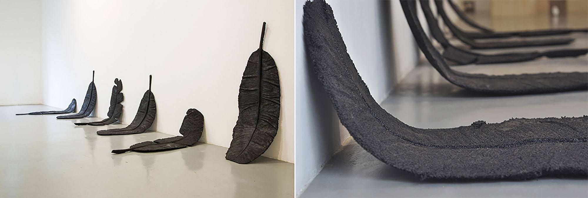 Banana leaves cast in rubber resting against a gallery wall