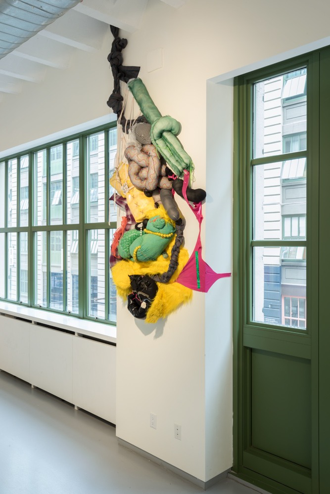 An installation image of an artwork hung on the wall made from cushions and fabric