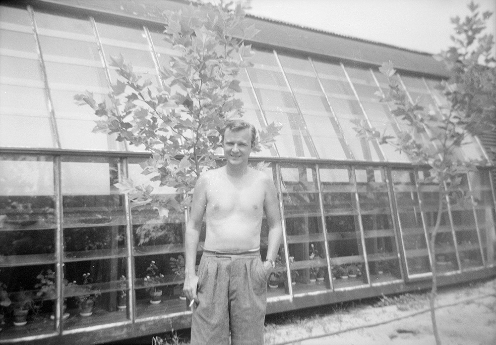 Robert Motherwell as a young man standing in front of a structure with glass windows