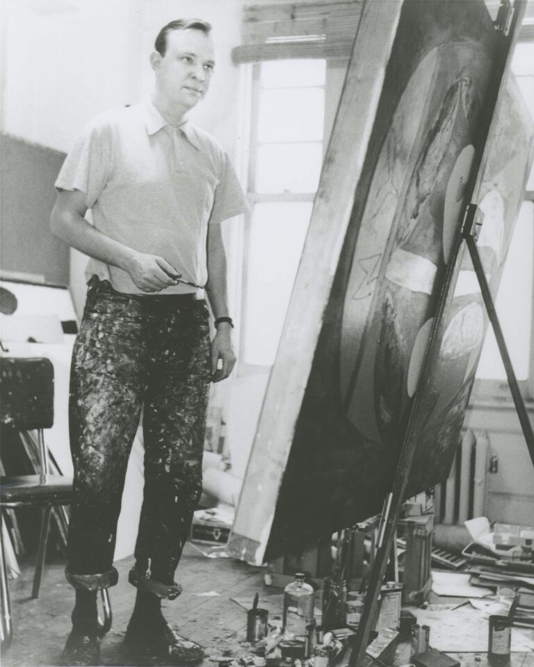 Robert Motherwell holding a paintbrush in front of his painting easel in Fourth Avenue studio, 1950