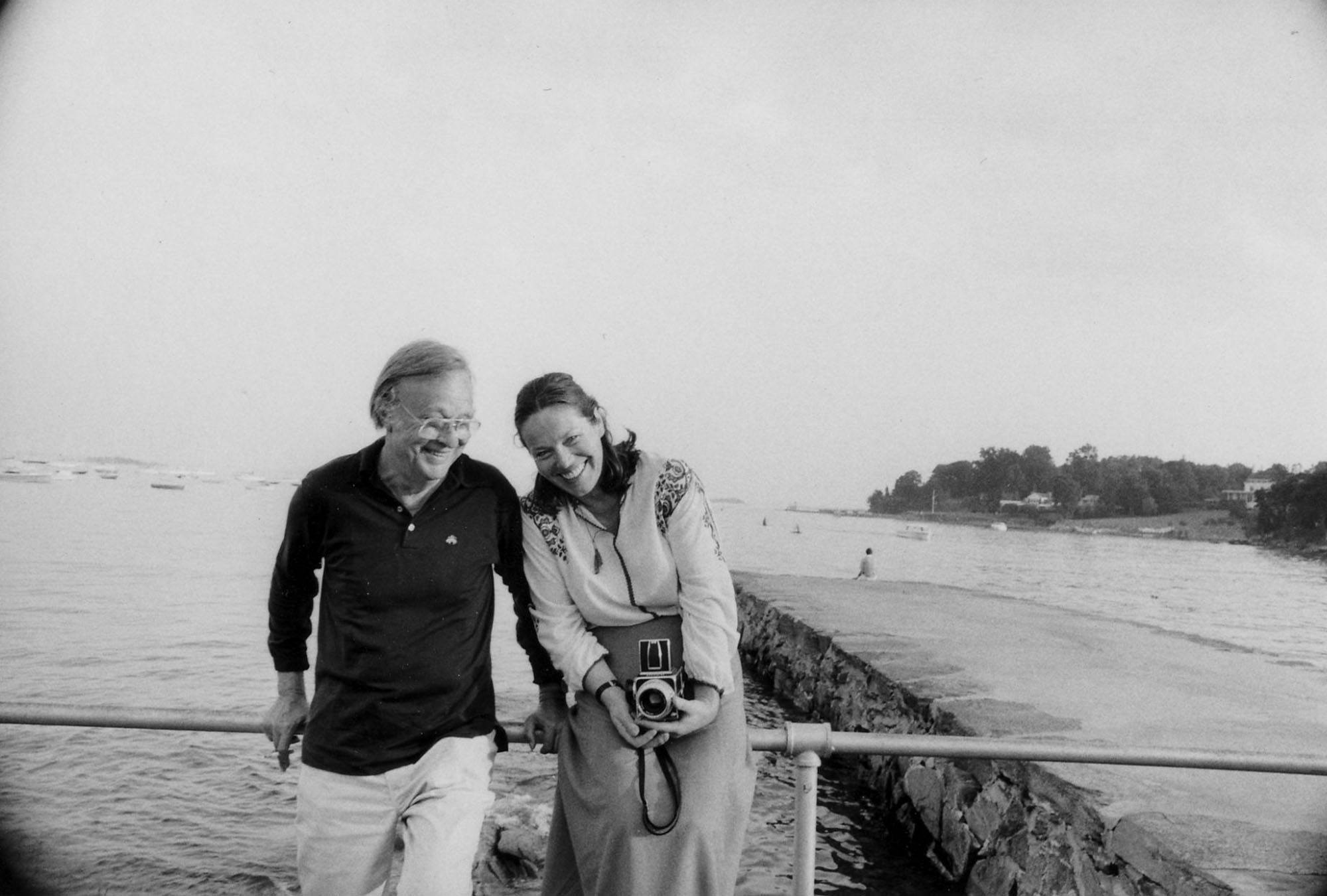 Robert Motherwell and Renate Ponsold laughing at the seaside during the 1980s. Ponsold holds a camera.