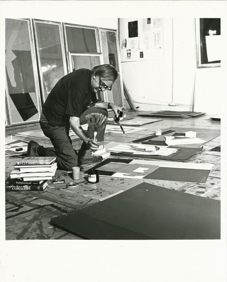 Robert Motherwell on one knee working on a collage on the floor of his studio, 1976