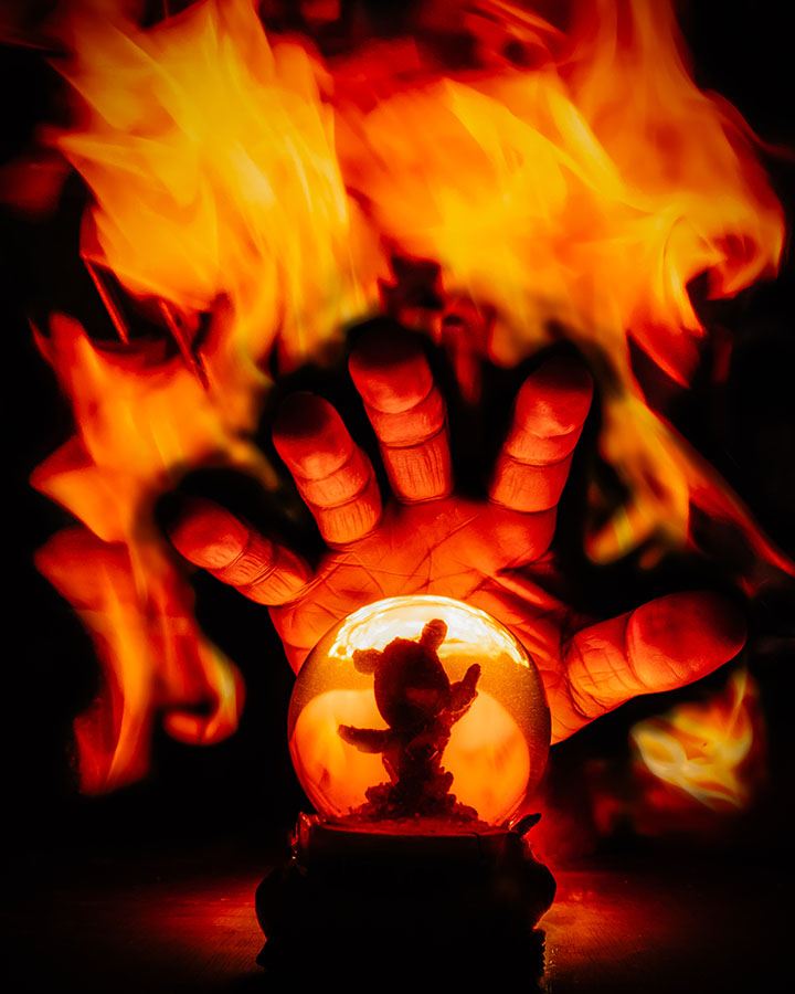 A hand protecting a small globe from fire